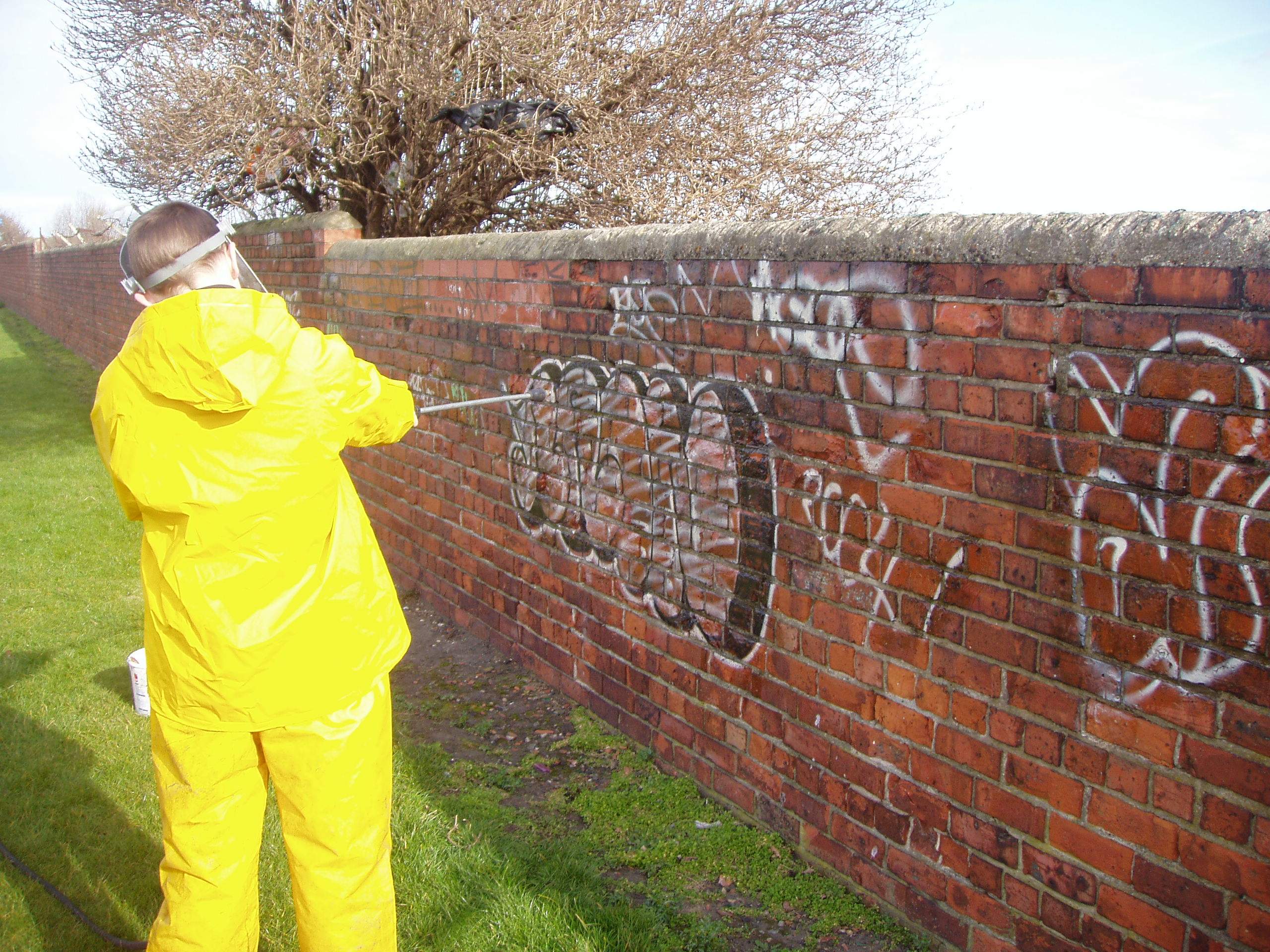 Pressure washing graffiti on wall